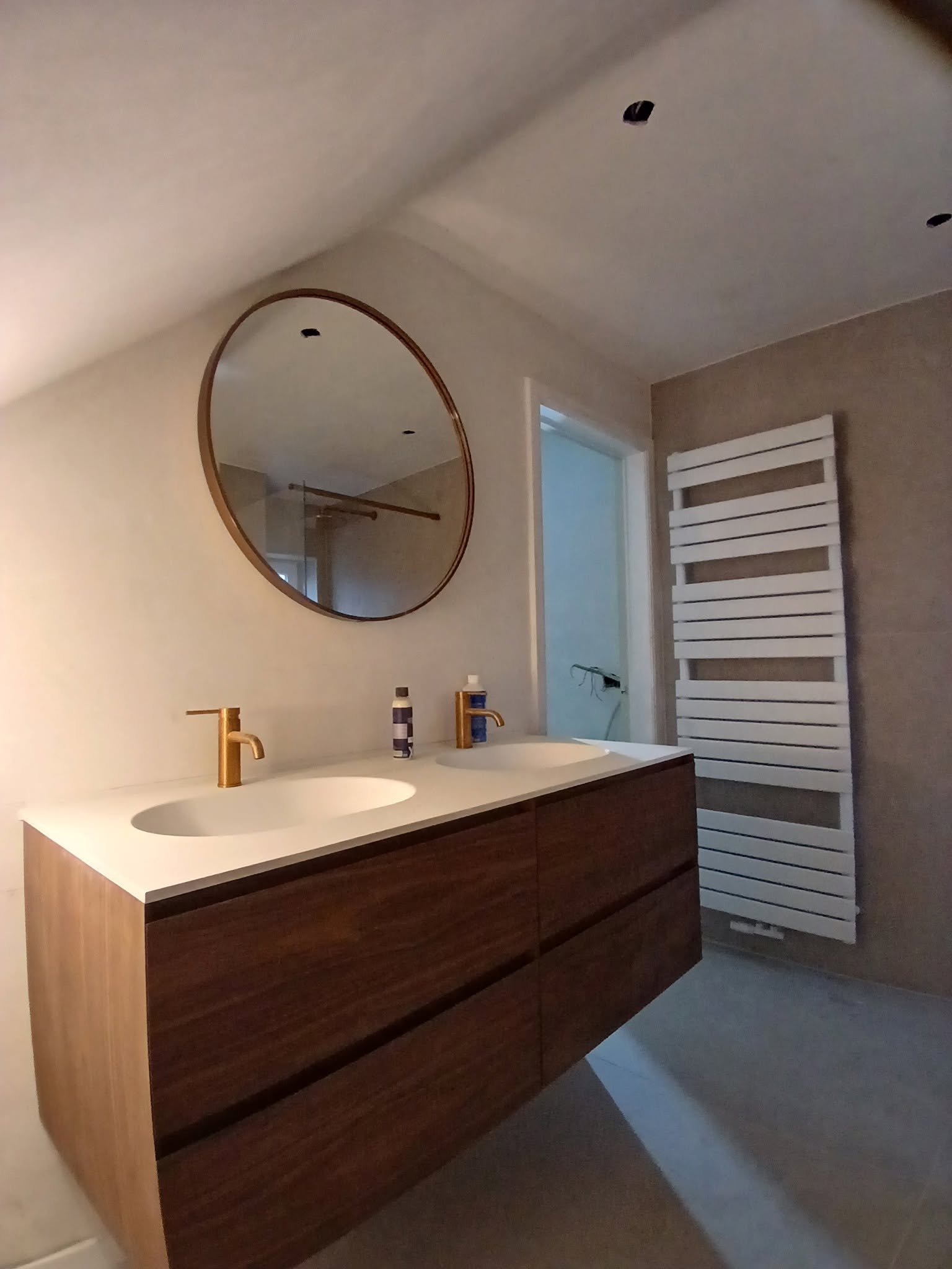 Aménagement salle de bain avec meuble vasque en bois et miroir rond